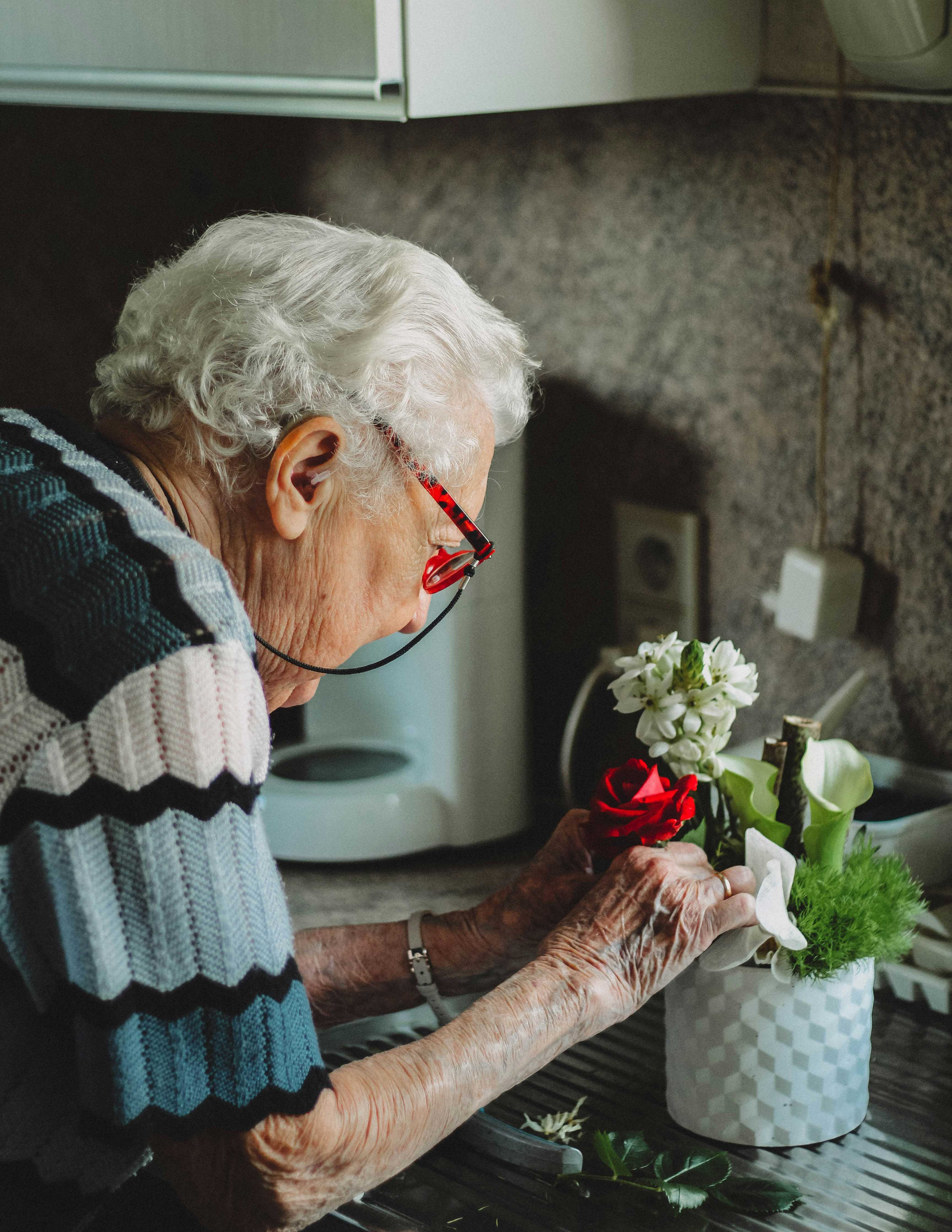 Older woman arranging flowers at home
